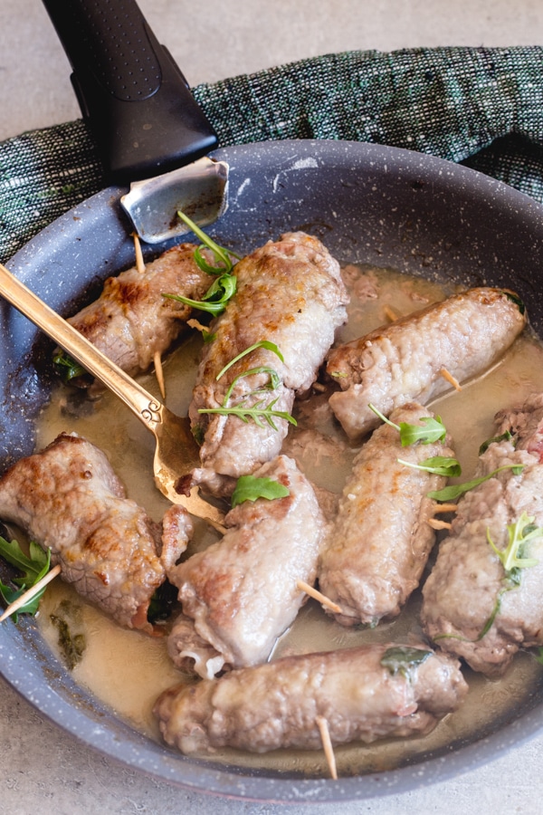 cooked involtini in a black pan with a gold fork