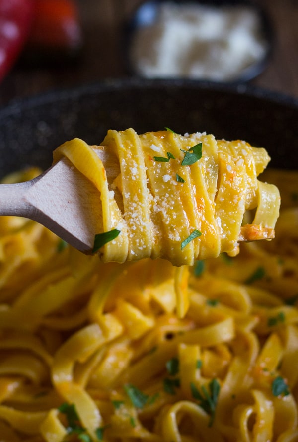 upclose pasta and pepper cream sauce on a wooden fork