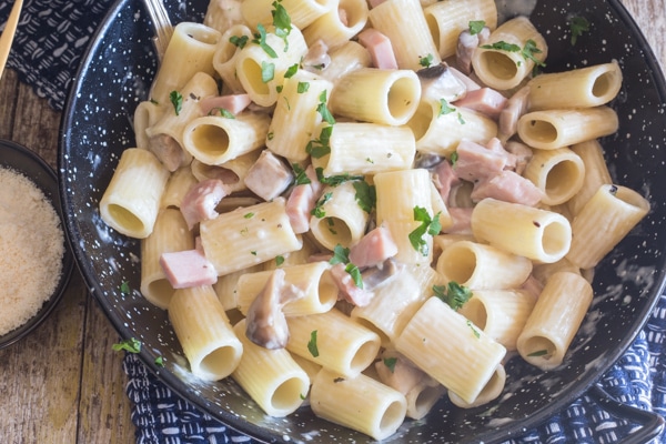 up close mushroom & ham pasta in a black pan