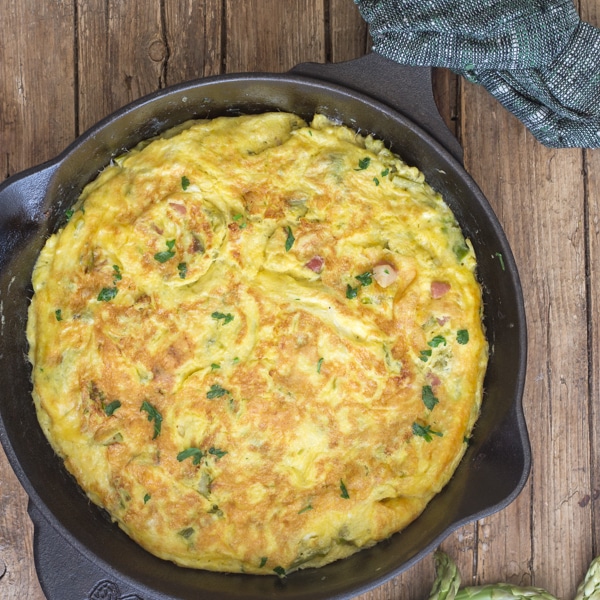 asparagus frittata in a skillet on a wooden board