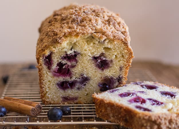 a slice cut from blueberry streusel loaf on a wire rack