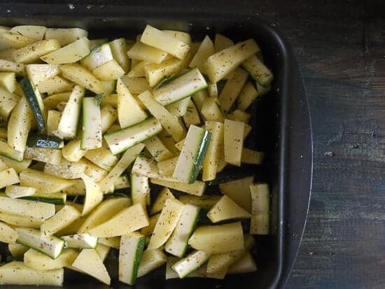 trai a abobrinha em fatias de batata numa assadeira