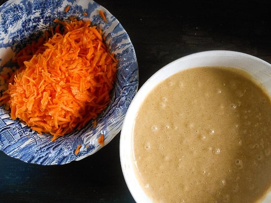 shredded carrots in a bowl and mixed cake batter in a white bowl