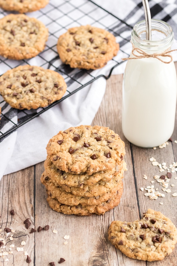 oatmeal chocolate chip cookies stacked on a wooden with a bottle of milk