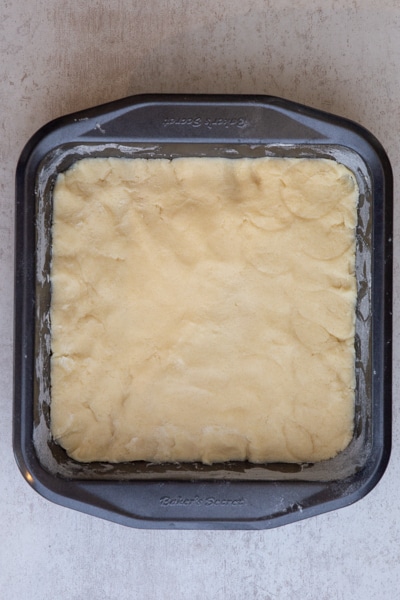 The base spread in the prepared square cake pan.