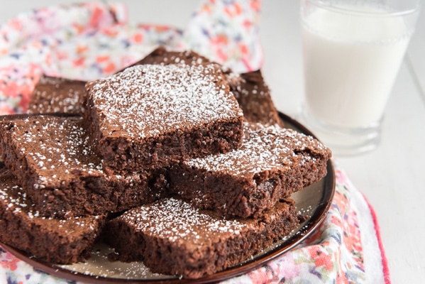 brownies cut and stacked on a plate with a glass of milk