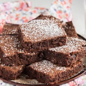 brownies cut and stacked on a plate dusted with powdered sugar