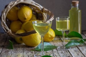 limoncello in two glasses with lemons in a basket
