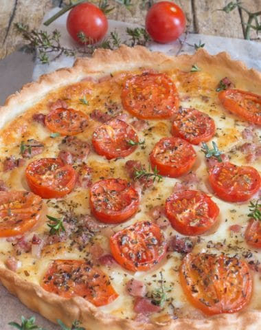 savory pie with tomatoes pancetta and mozzarella on a wooden board