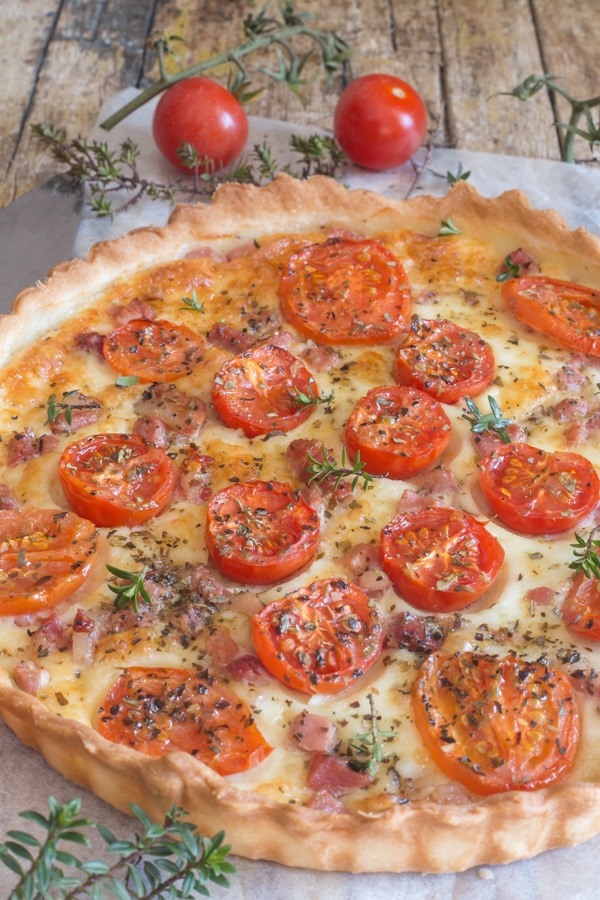 savory pie with tomatoes pancetta and mozzarella on a wooden board
