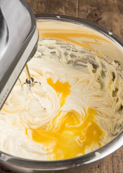 Beating the eggs into the cream cheese mixture.