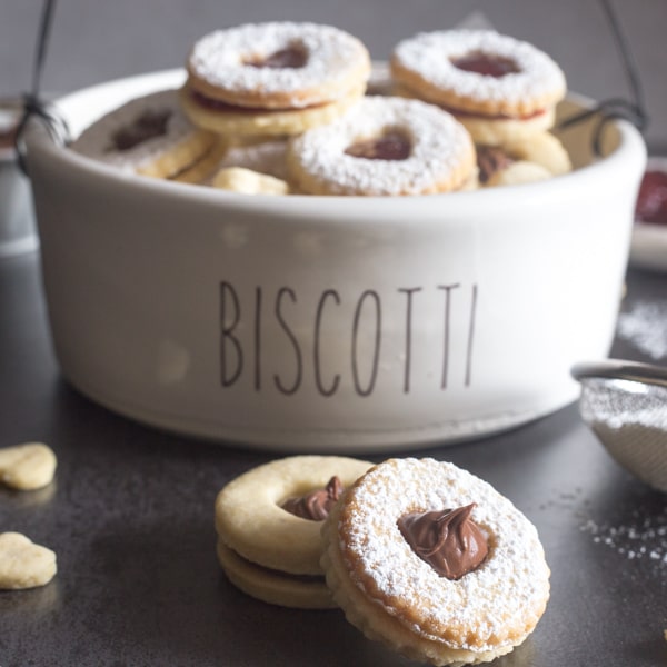 Italian sandwich cookies in a bowl and 2 on a black board