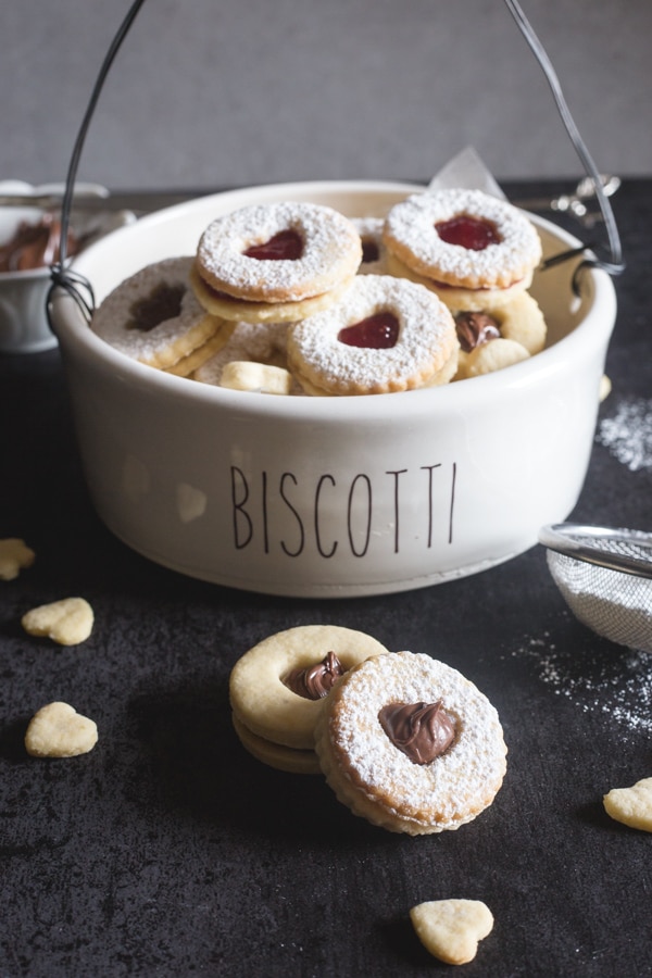 Italian sandwich cookies in a bowl and 2 on a black board