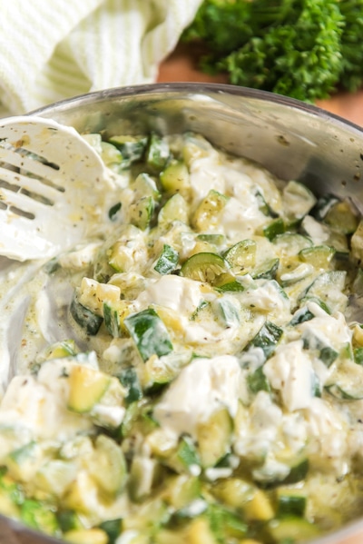 mixing the zucchini & cream cheese in the pan with a white spoon