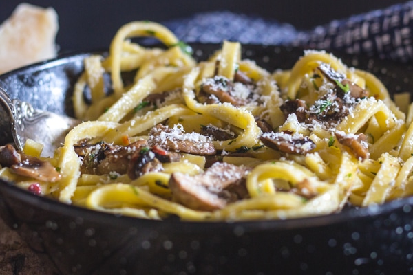 mushroom pasta in a pan sprinkled with parmesan cheese