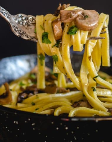 mushroom fettuccine in a black pan with a forkful of pasta