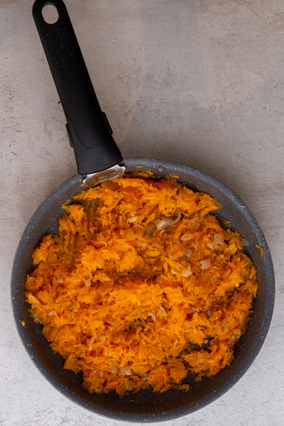 Adding the pumpkin puree to the black pan.