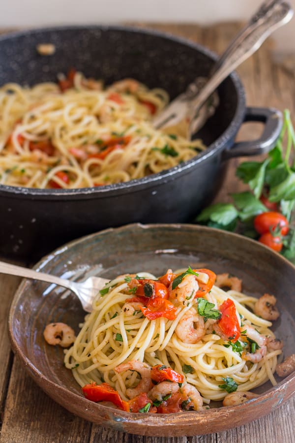 shrimp and tomato pasta in a dish and in a black pot