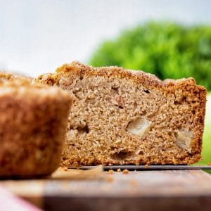 Apple loaf on a board with a slice cut.