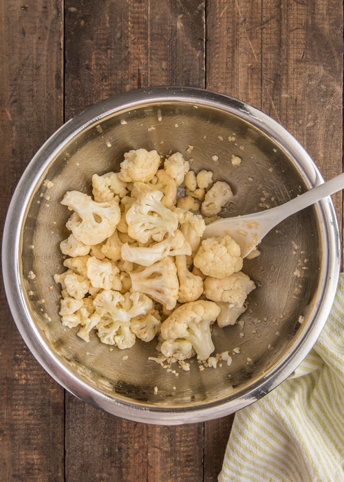 Mixing the cauliflower in a silver bowl.