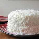 Coconut Cake, a delicious soft, moist cake with a creamy cream cheese frosting. Topped with coconut flakes, a perfect Christmas dessert.