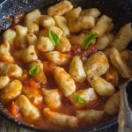 potato gnocchi in a black pan tossed with tomato sauce