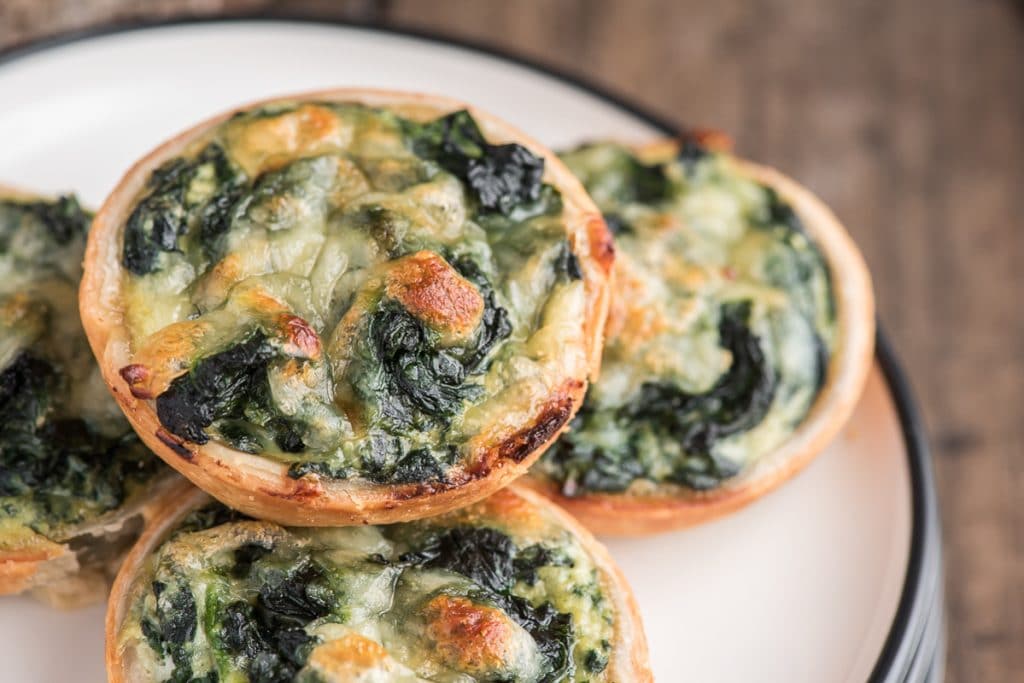 Ricotta spinach tarts on a white plate.