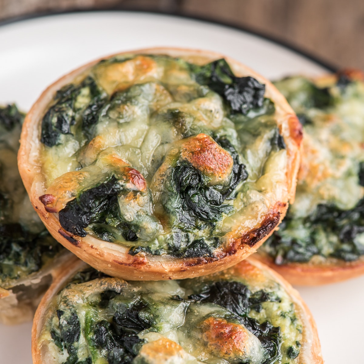 4 ricotta spinach tarts on a white plate.