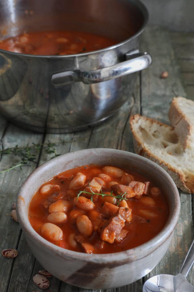 Prosciutto soup in a blue bowl and in a silver pot.