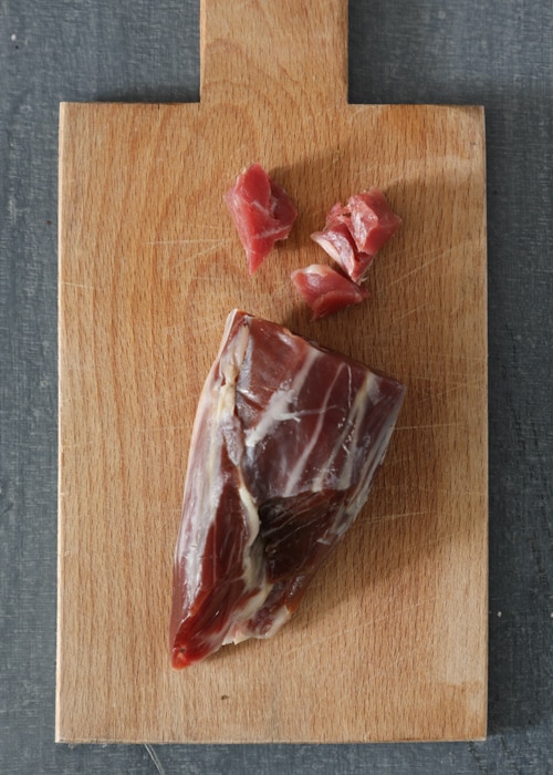 Cutting the prosciutto on a wooden board.