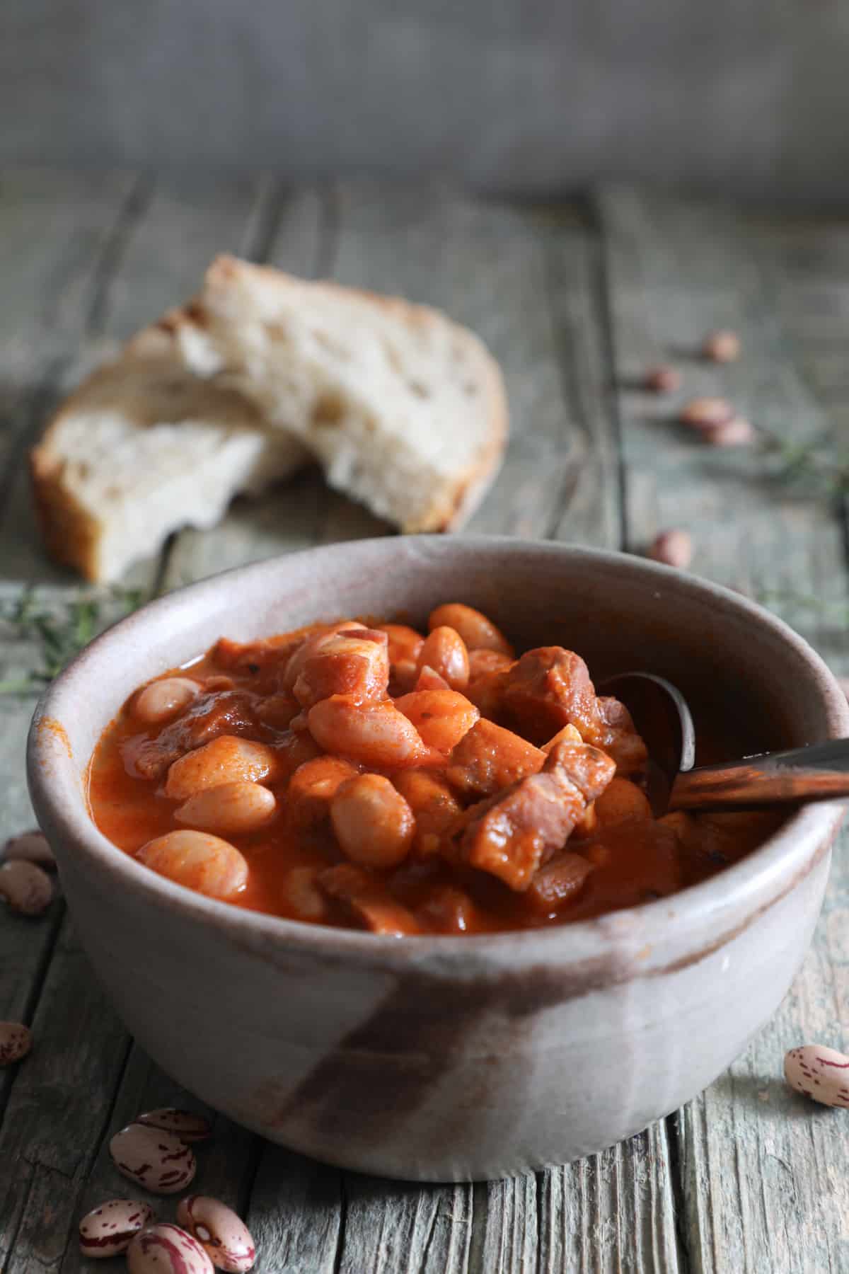 Prosciutto bean soup in a blue bowl with two slices of bread.