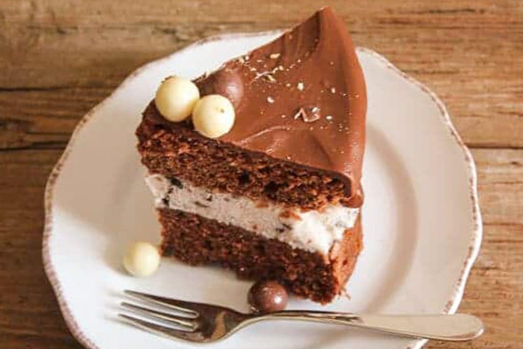 A slice of ice cream cake on a white plate with a fork.