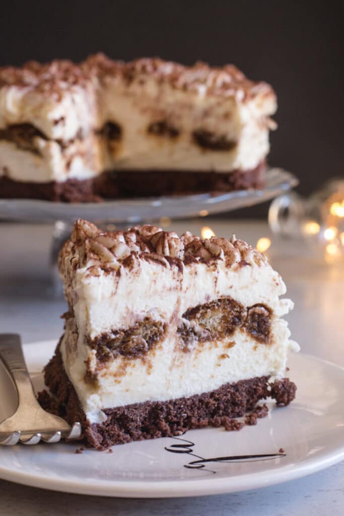 No bake tiramisu cheesecake on a glass dish and a slice on a plate.