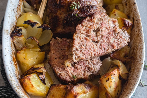 italian meatloaf with potatoes sliced in a pan