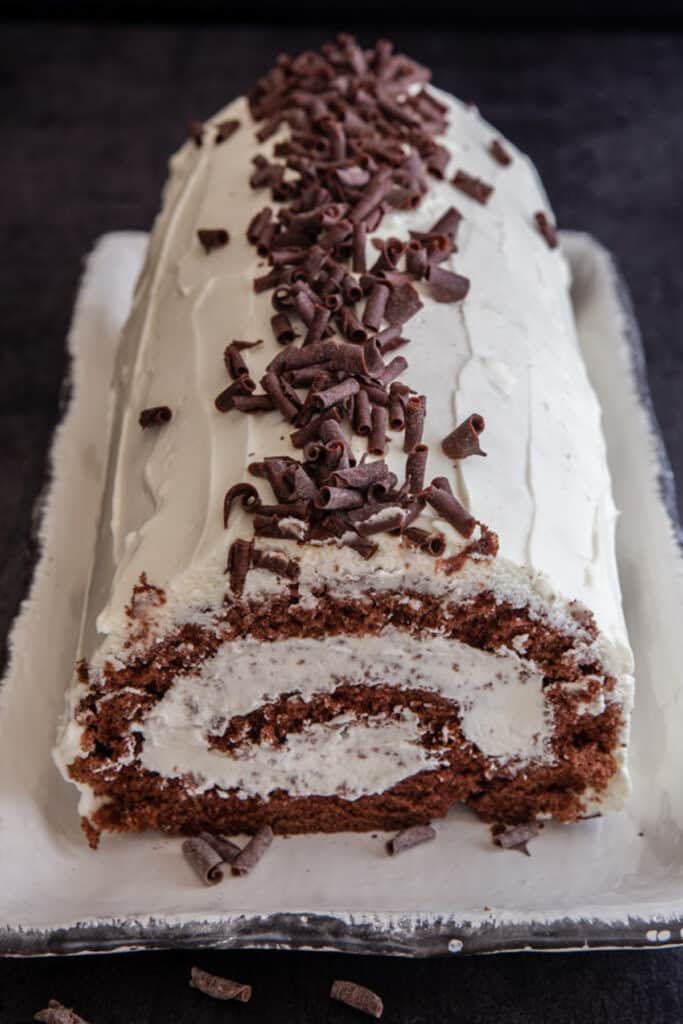 Tiramisu roll cake on a white tray.