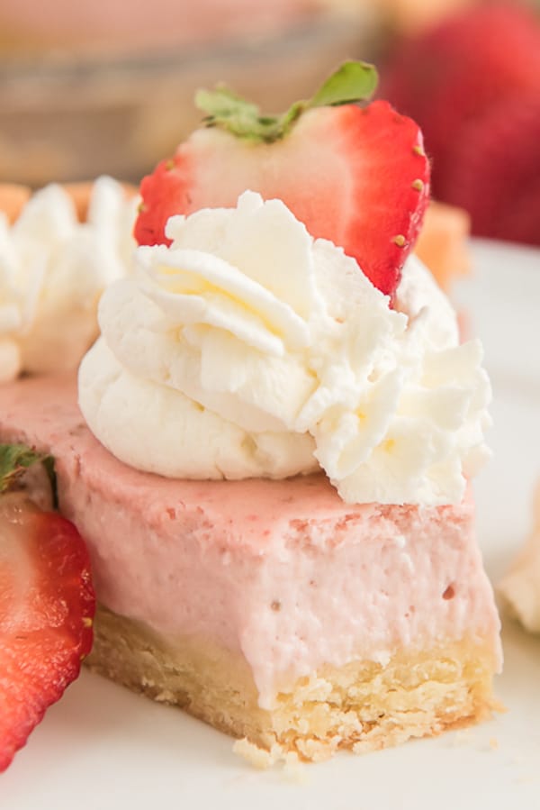 sliced pie with a forkful removed topped with whipped cream and a strawberry slice