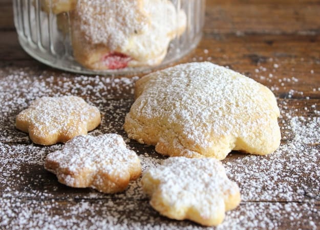 strawberry filled cookies on a wooden board sprinkled with powdered sugar