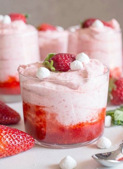 4 glasses of strawberry mousse. on a white board with a spoon
