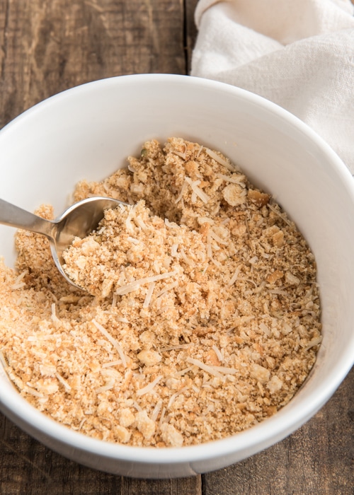 Combining the bread crumb topping in a white bowl.