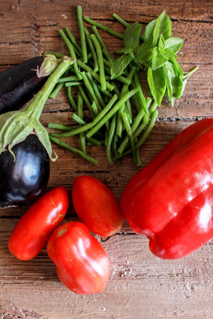 Beans, eggplant, tomatoes & pepper on a brown board.