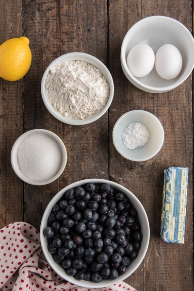 Ingredients to make a blueberry pie on a wooden board.