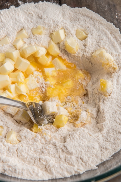 The dry ingredients in a glass bowl with butter and egg in the middle.
