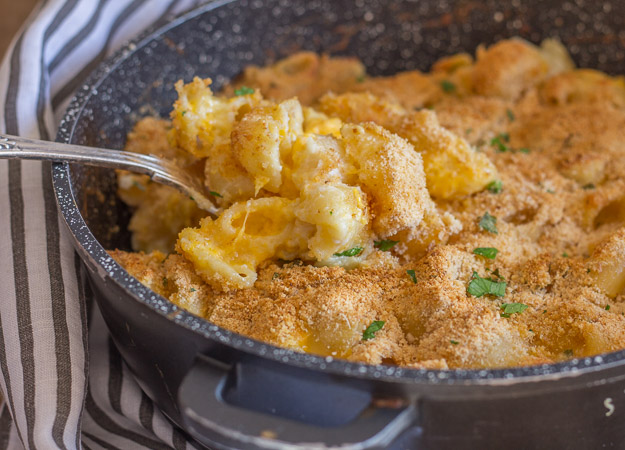 baked macaroni double cheese in a skillet with a spoonful