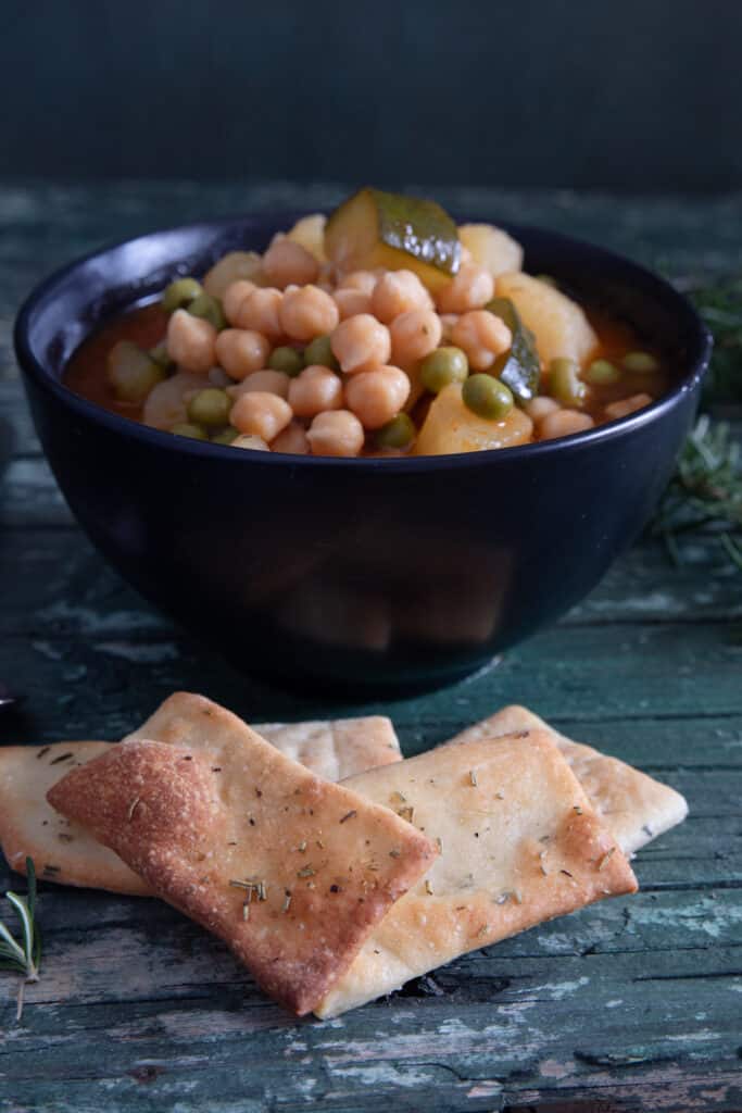 Soup in a bowl with crackers on a wooden board.