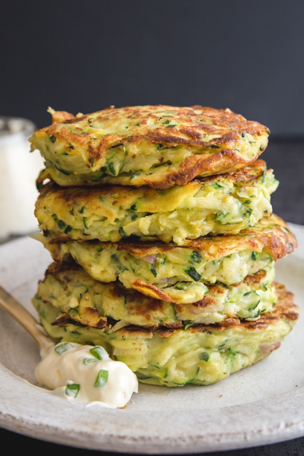 5 patties stacked on a white plate with a spoon of mayo