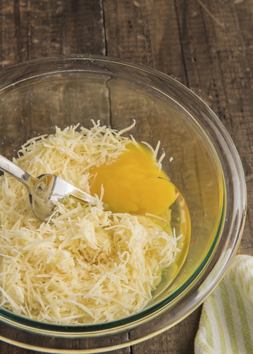 Mixing the egg and cheese in a glass bowl.