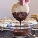 dipping a chocolate hazelnut shortbread cookie into some melted chocolate
