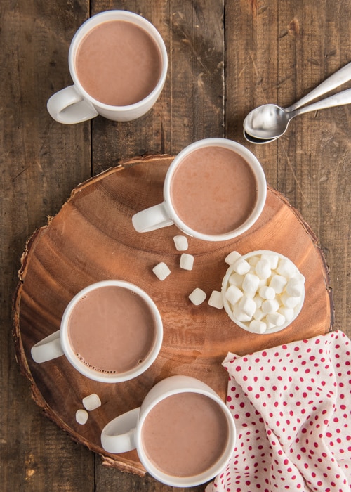 Hot chocolate in the cups with mini marshmallows in a bowl.