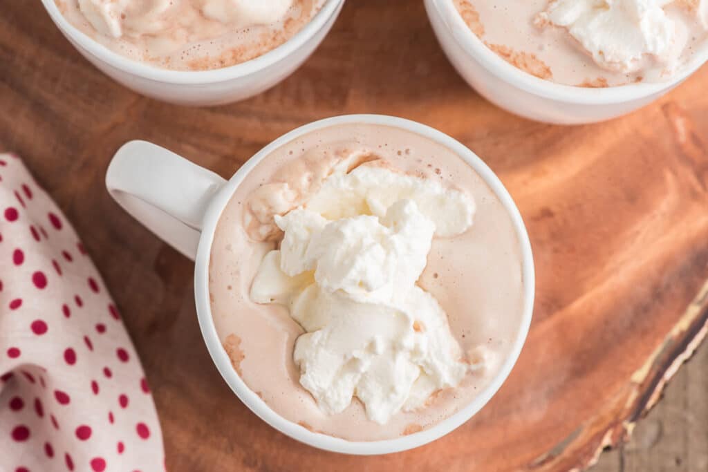 Hot chocolate with whipped cream on top in three white cups.