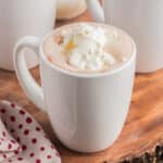 Hot chocolate with whipped cream on top in three white cups.